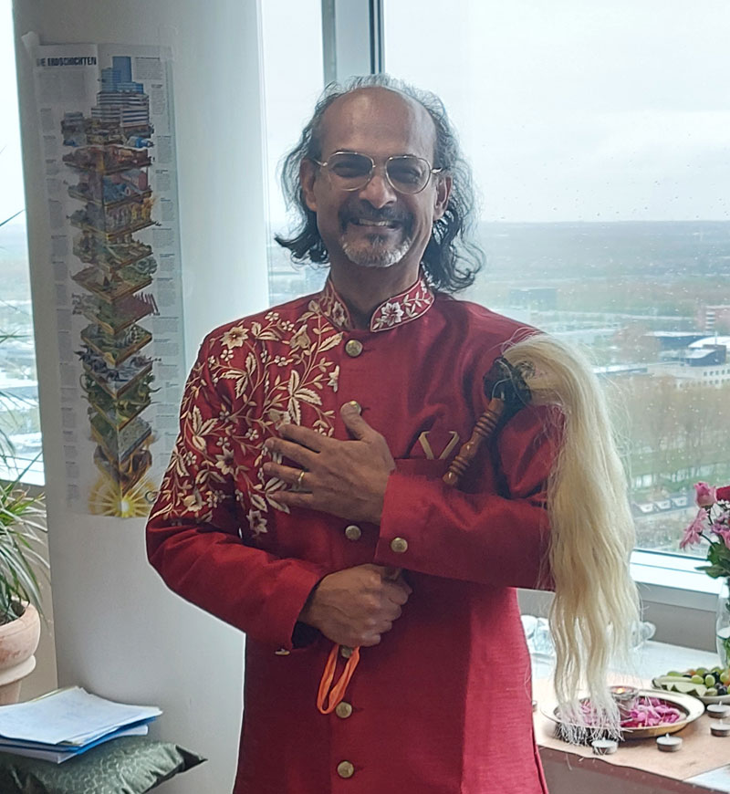 Aniel Ramjanam in een rode jas voor een raam met uitzicht