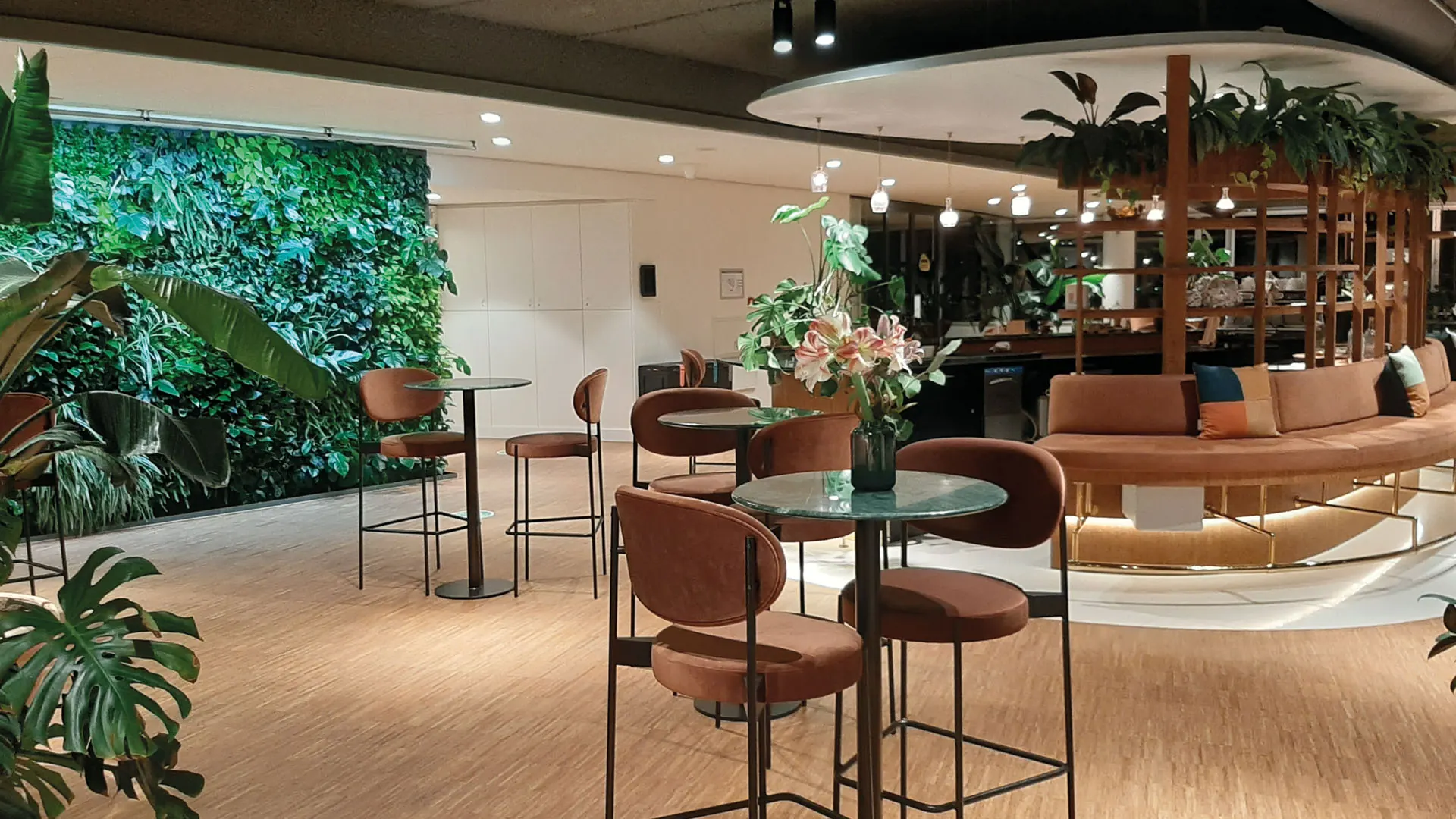 Statafels met terracotta stoelen en een groene wand in Pharos