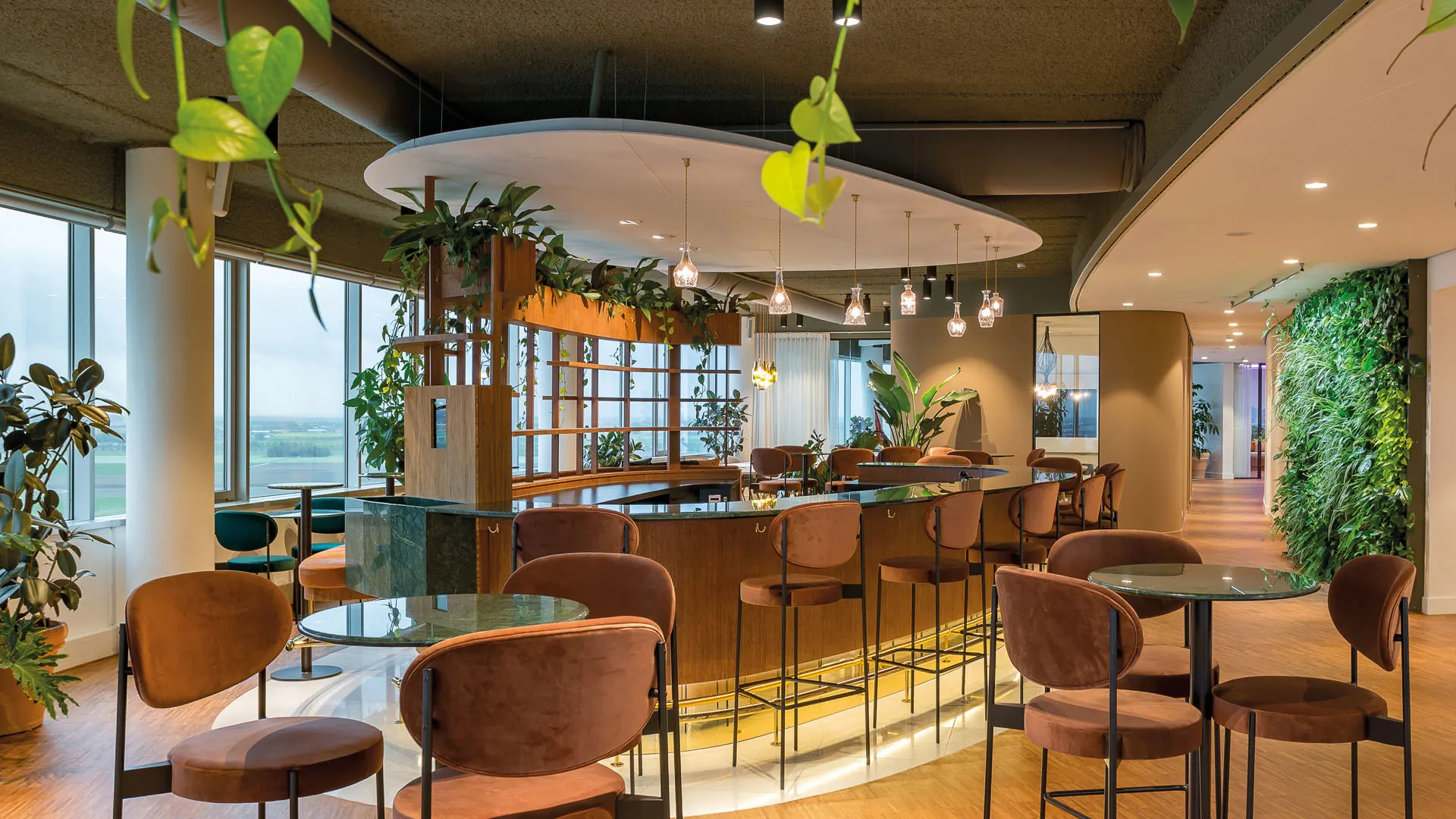 Ronde bar in Pharos met planten, hanglampen en terracotta stoelen