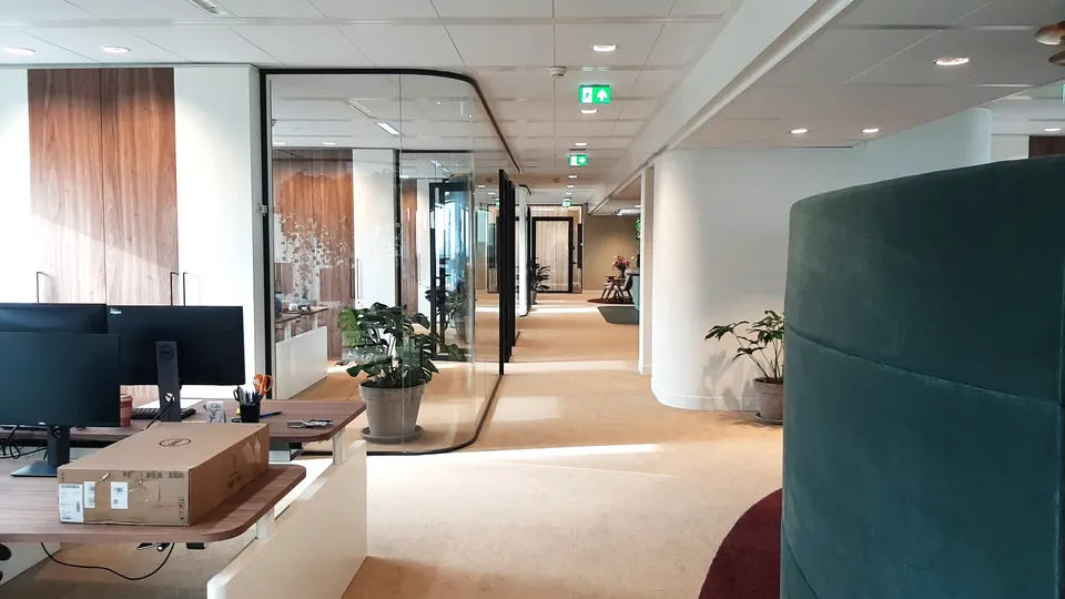 Werkplekken en een gang met houten wanden in het kantoor van Schroders Real Estate